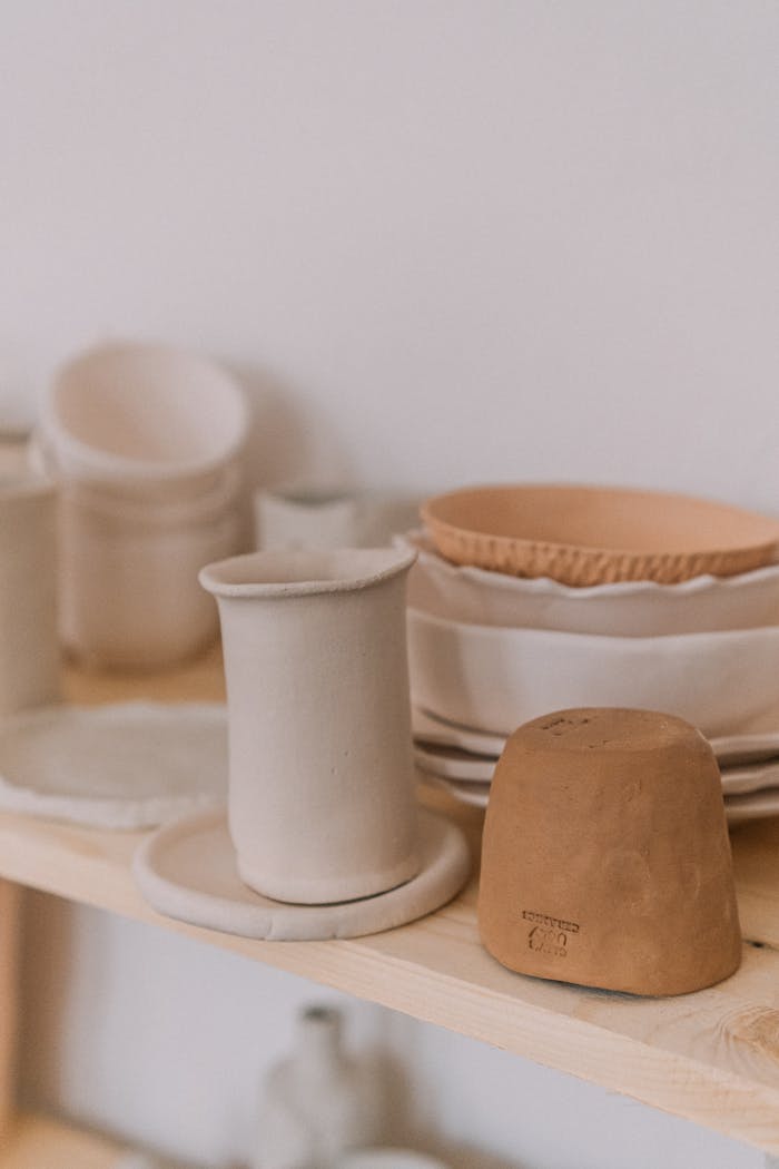 A collection of handmade ceramic dishes arranged on a rustic wooden shelf.