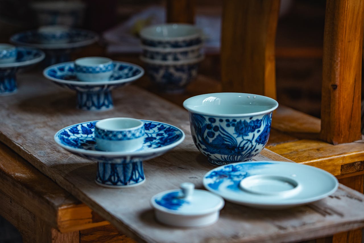 Elegant blue and white porcelain tableware set on a rustic wooden table indoors.